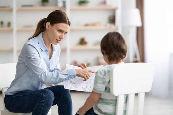 אשת מקצוע יושבת עם ילד ומביטים בציור שצייר